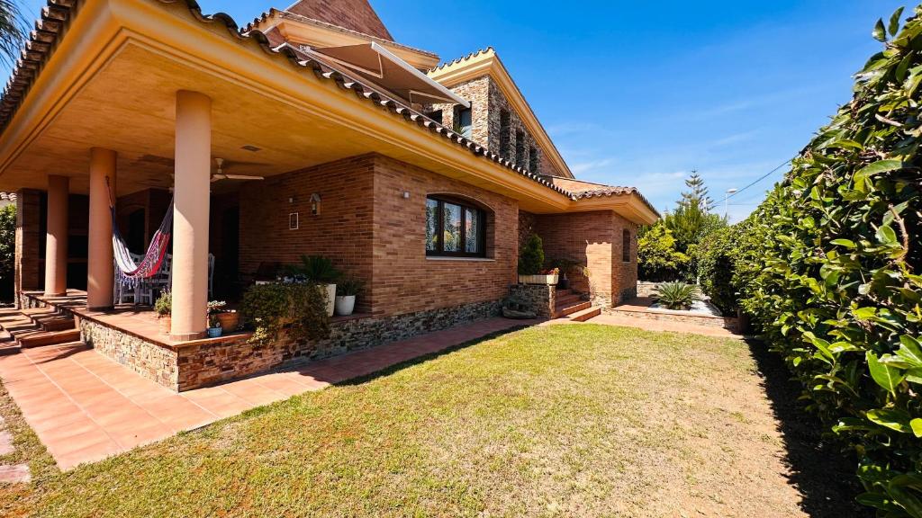 a brick house with a lawn in front of it at Hermosa Villa L'Ardiaca in Cambrils