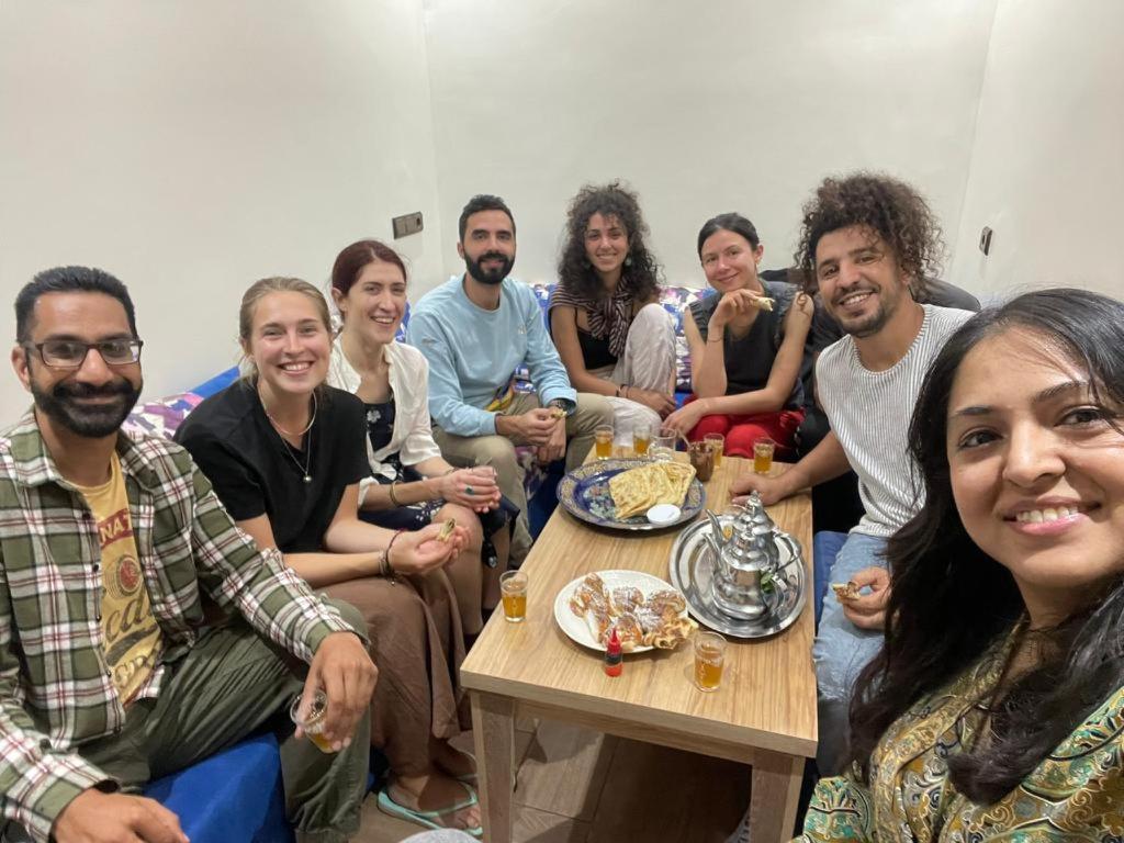 Un groupe de personnes assises autour d'une table avec de la nourriture dans l'établissement Moroccan Family House, à Agadir