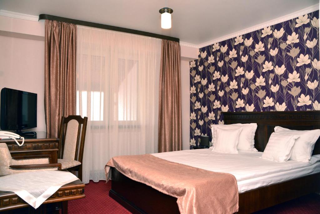 a bedroom with a bed with a floral wallpaper at Hotel President in Satu Mare
