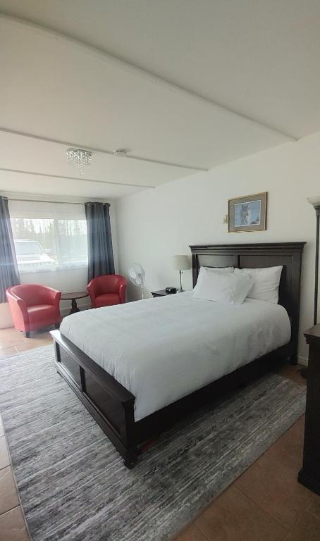 1 dormitorio con 1 cama grande y 1 silla roja en White Fang Motel, en Wawa