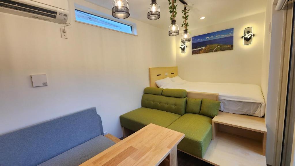 ein kleines Zimmer mit einem Sofa und einem Bett in der Unterkunft ZUMI TERRACE うちなーみやリゾート宮古島 in Miyako-jima
