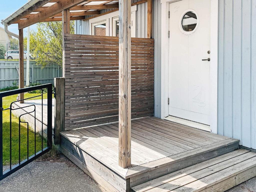 eine hölzerne Veranda mit einer weißen Tür und einem Zaun in der Unterkunft Holiday home ELLÖS VII in Ellös