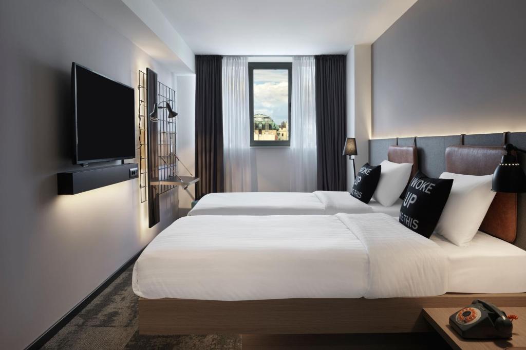 a bedroom with a large bed and a flat screen tv at Moxy Belgrade in Belgrade