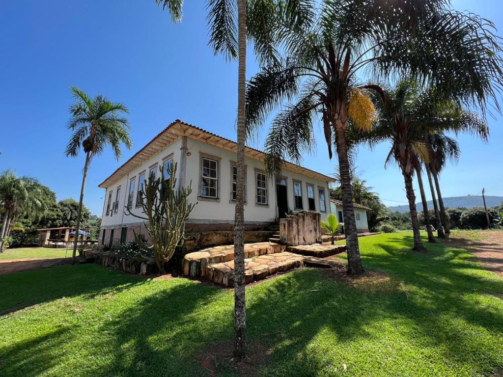 een wit huis met palmbomen ervoor bij Pousada Fazenda São Pedro in Delfinópolis