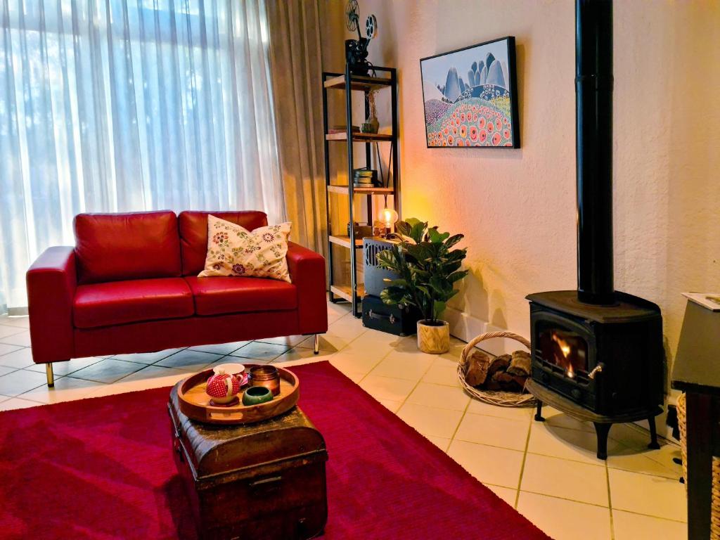 uma sala de estar com um sofá vermelho e um fogão a lenha em Intermission at Queenscliff em Queenscliff
