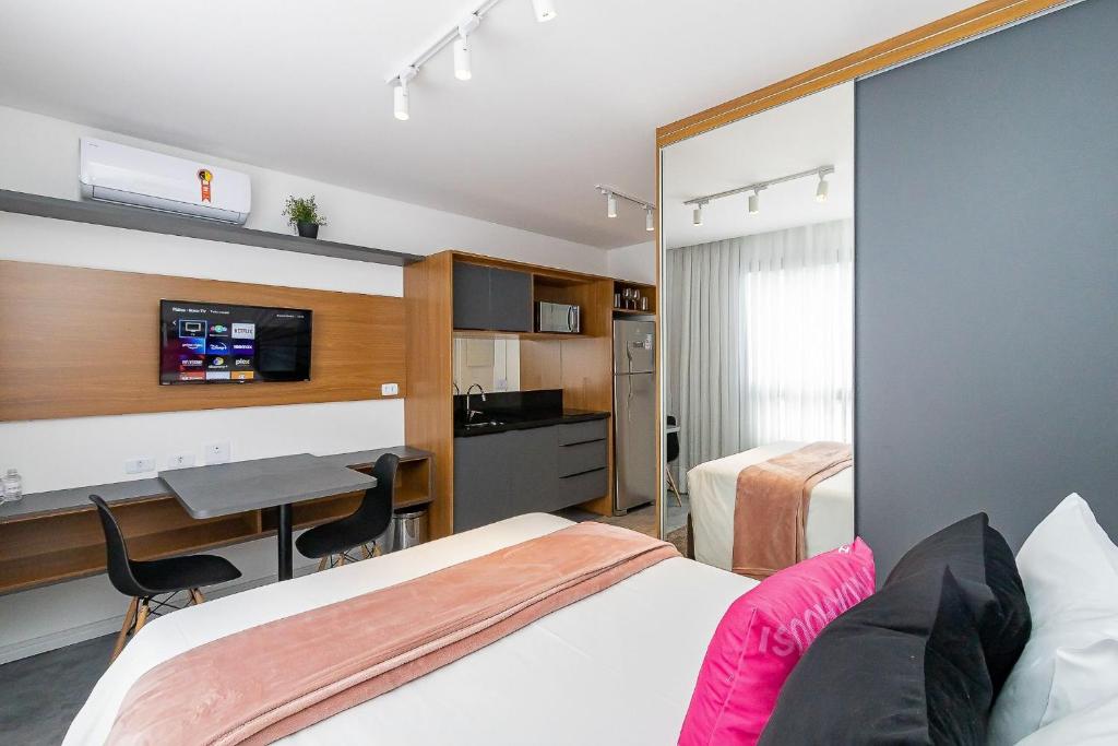 a hotel room with a bed and a desk and a tv at Housi Brickell One Com Vaga - HBO0201 V13 in Curitiba