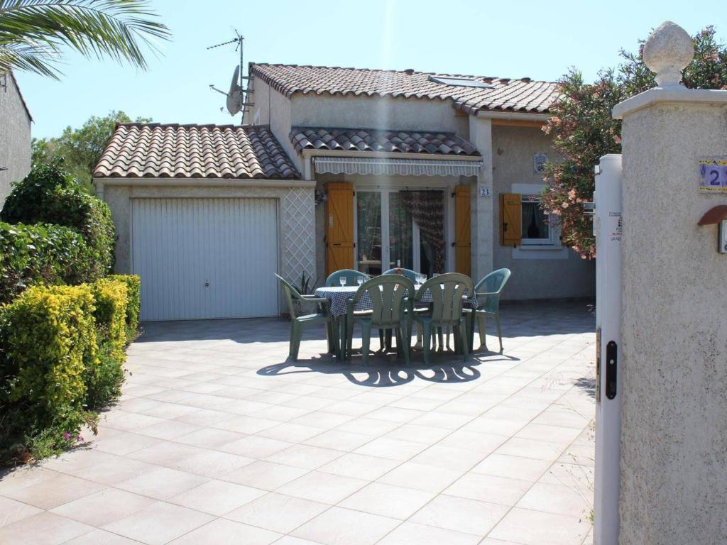 un patio avec une table et des chaises devant une maison dans l'établissement Villa spacieuse 3 pièces avec mezzanine, 6 couchages, proche plage, commerces et balnéothérapie - FR-1-229-855, à Gruissan