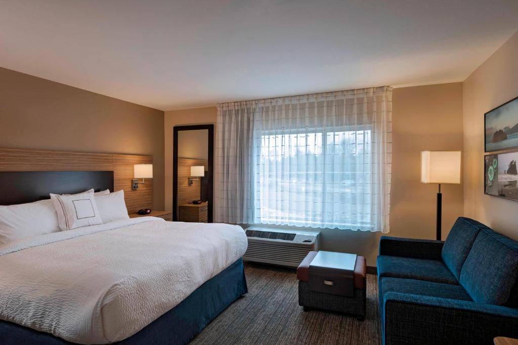 a hotel room with a bed and a blue couch at TownePlace Suites by Marriott Tacoma Lakewood in Lakewood