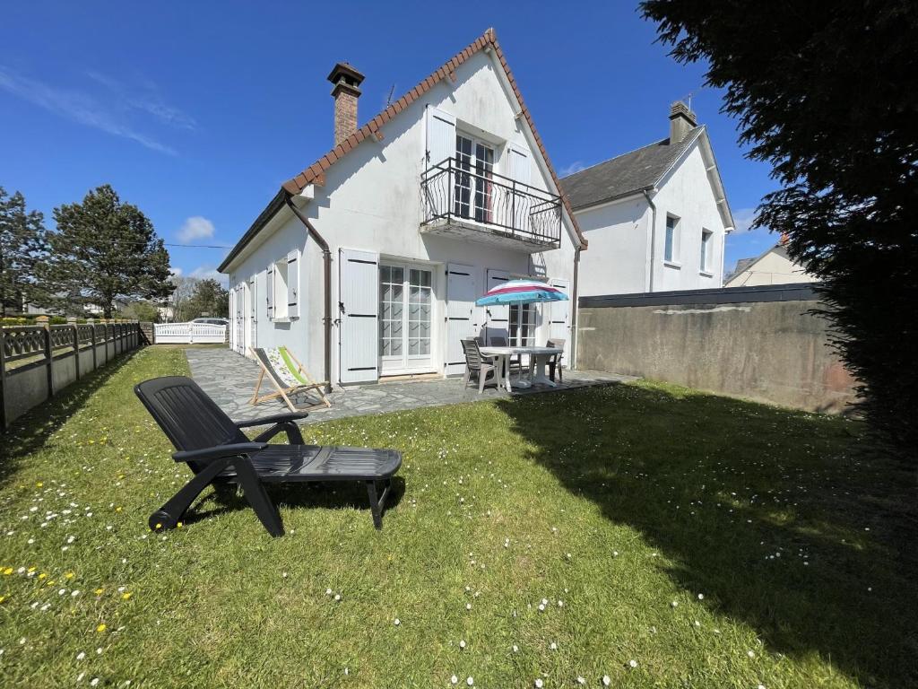 une maison avec une chaise et un parasol dans la cour dans l'établissement Maison avec jardin clos, à 600m de la plage, 4 chambres, barbecue, proche commerces et attractions - FR-1-361-495, à Jullouville