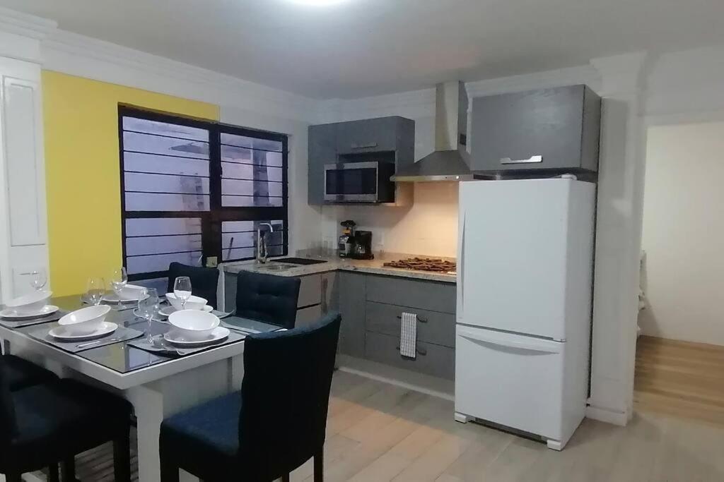 uma cozinha com uma mesa e um frigorífico branco em Disfruta de cómodo y bello departamento em Guadalajara