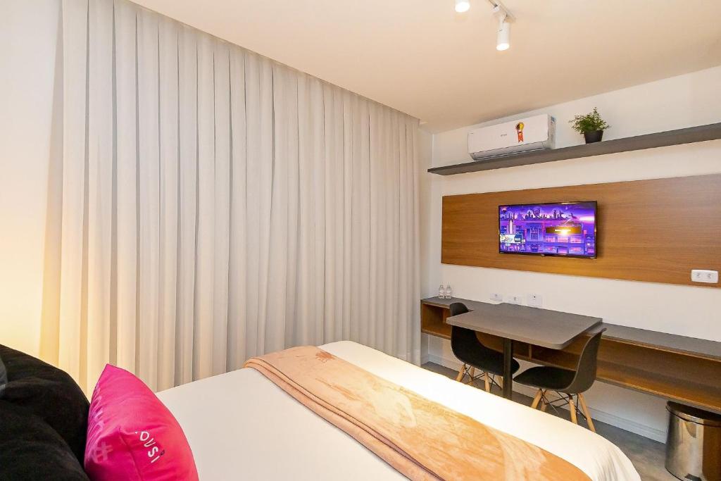 een hotelkamer met een bed en een tafel en een televisie bij Housi Brickell One Com Vaga - HBO0606 V12 in Curitiba