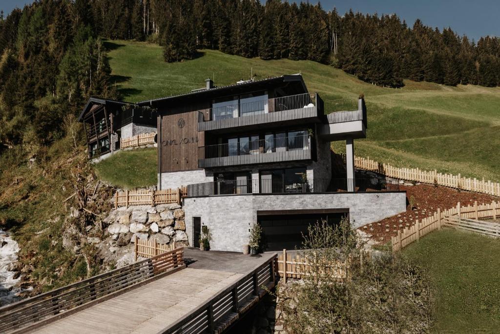 ein Haus auf einem Hügel mit einer Holzbrücke in der Unterkunft ONKL XONNA Premium Alpin Chalets in Hüttschlag