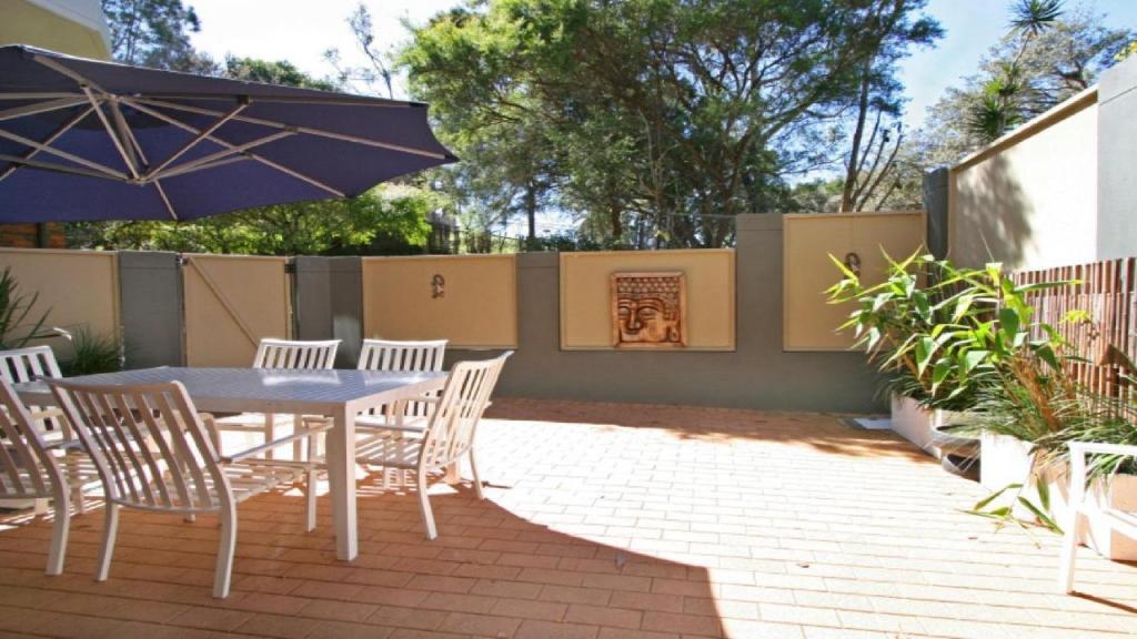 a patio with a table and chairs and an umbrella at Terrigal Tranquility Pool In Complex, In The Heart Of Terrigal in Terrigal