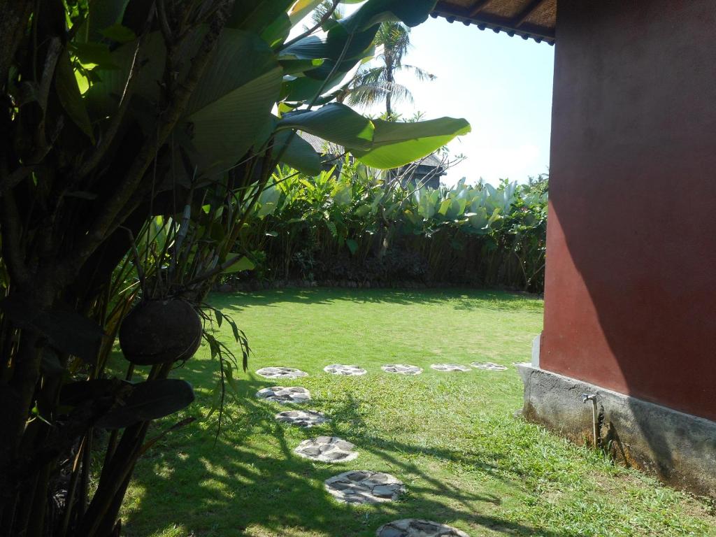 a yard with a lawn with rocks in the grass at Cegeng Lestari Guesthouse in Sidemen