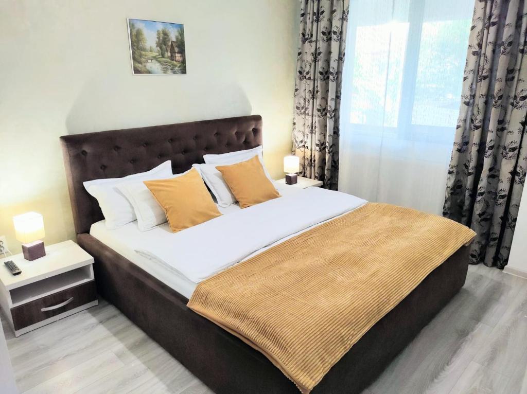 a bedroom with a bed with white sheets and orange pillows at Simona Apartament Palas Mall 1 in Iaşi