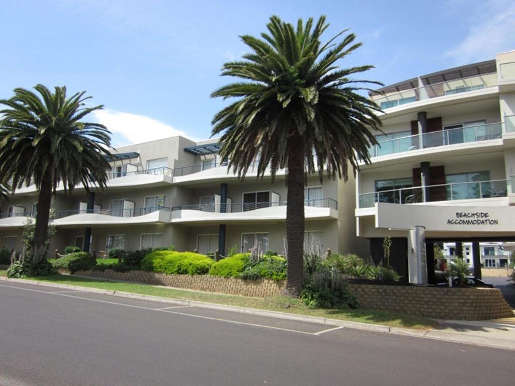 un bâtiment avec des palmiers devant une rue dans l'établissement The Waves Oasis, à Cowes