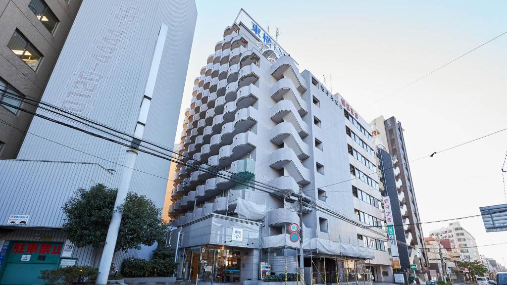een hoog wit gebouw in een stadsstraat bij Toyoko Inn Tsudanuma-eki Kita-guchi in Funabashi
