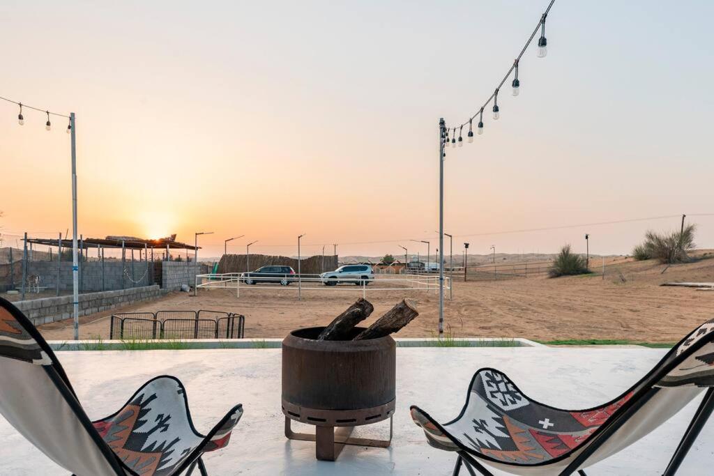 two chairs and a trash can with a baseball field at Desert farm gateway W/ pool & horse in Hunaywah