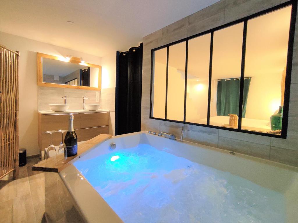 a large bath tub in a bathroom with a sink at Maison de ville, SPA Balnéo, 2 suites parentales in Vichy