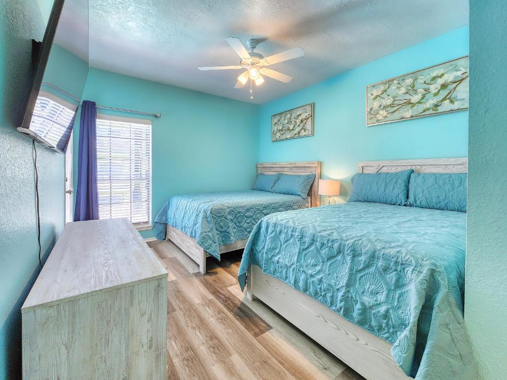 a bedroom with two beds and a ceiling fan at NEW!! 2BR 4 Beds Condo with Pool in Galveston
