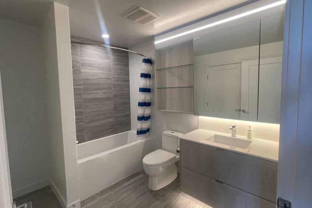 a bathroom with a white toilet and a sink at Brand New Starling Luxury Condo with Mountain Views in Burnaby