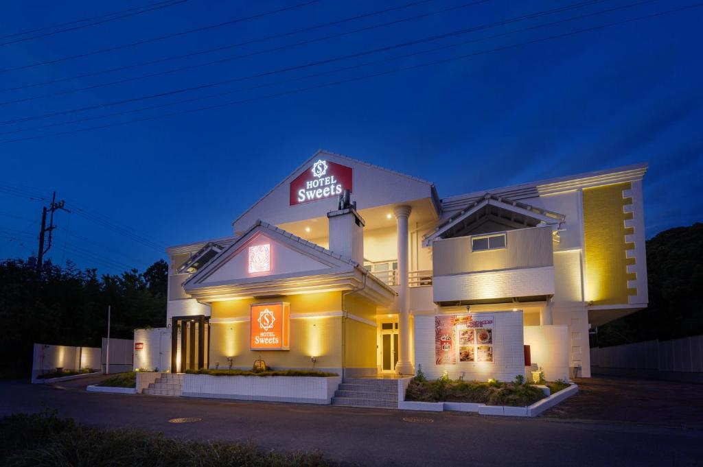 a large white building with a neon sign on it at HOTEL Sweets in Mobara