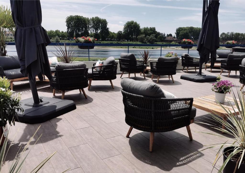 a patio with chairs and tables and a body of water at Mercure Nevers Pont De Loire in Nevers