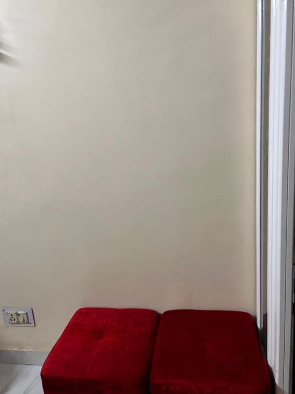 un divano rosso nell'angolo di una camera di Arora’s Mansion a Ghaziabad