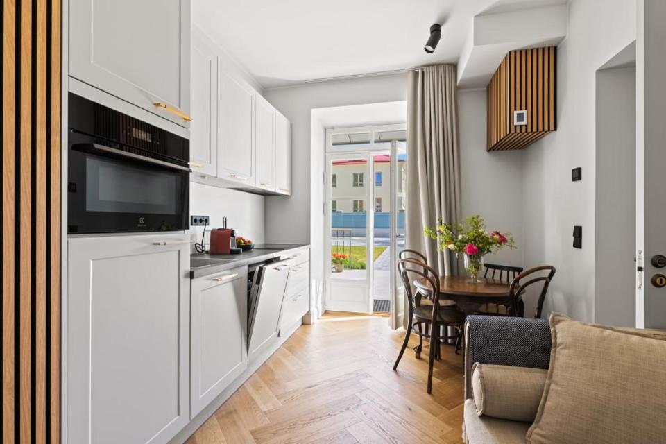 a kitchen with white cabinets and a table with chairs at Brand New Old Town Apartment With Terrace in Haapsalu