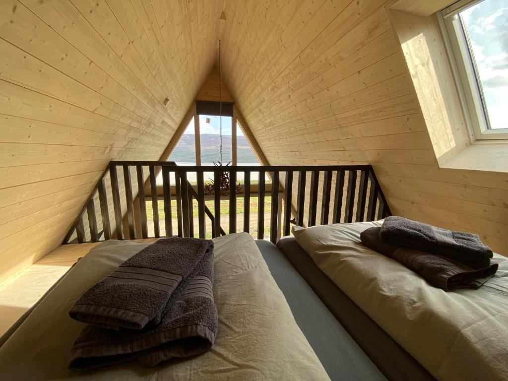 Hengifosslodge Tiny Houses في ايغلستادير: سرير في غرفة عليها منشفتين
