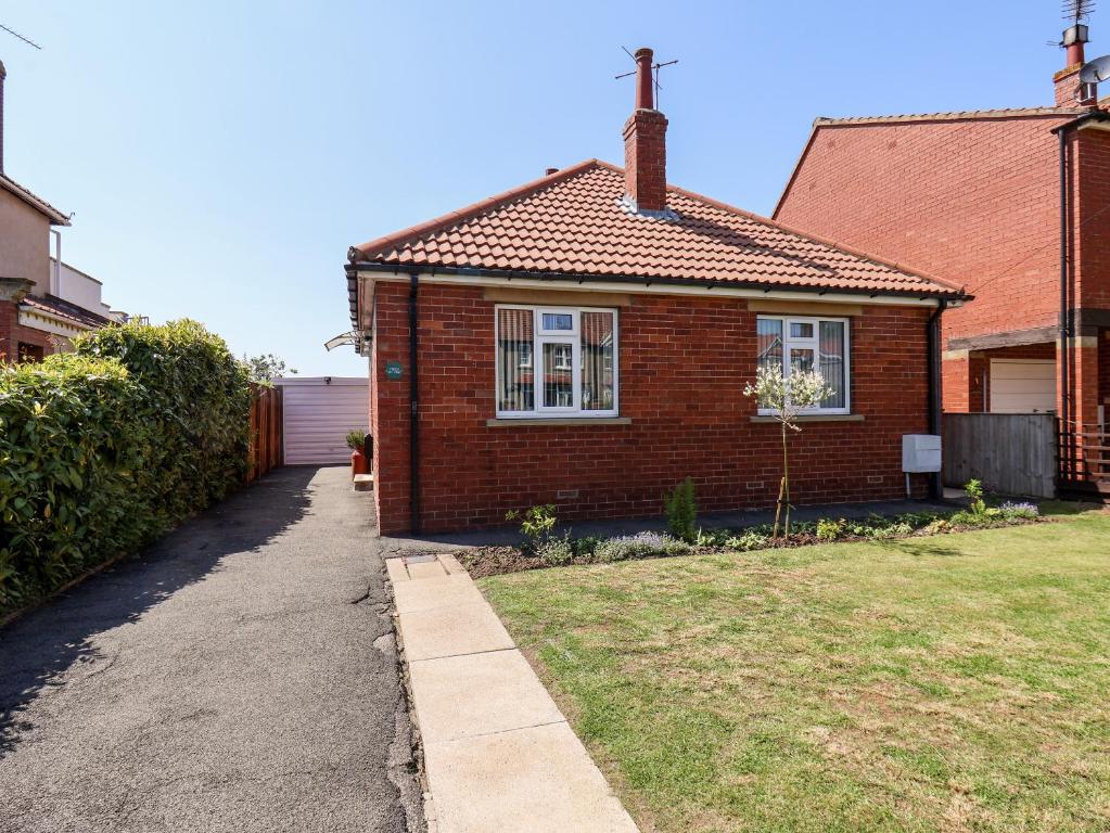 a red brick house with a grass yard at Field Cottage in York