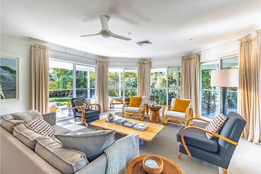 a living room with a couch and chairs and windows at Celeste 26 Bonito Street light filled pet friendly house in Corlette