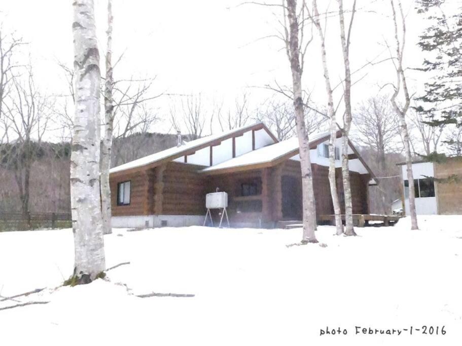 登别Noboribetsu Log House的雪中树下的小木屋