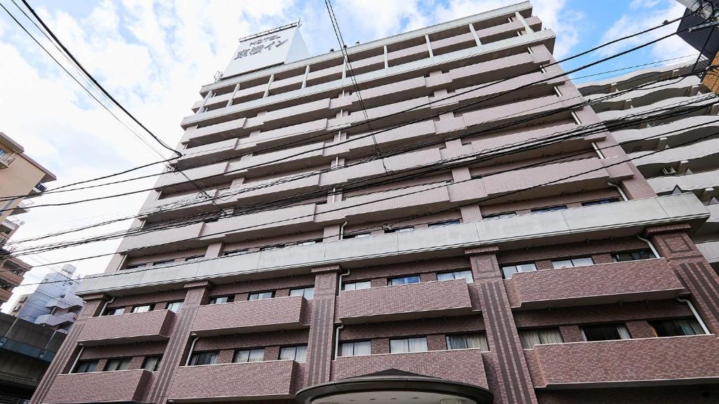 ein hohes Gebäude mit einer Flagge darüber in der Unterkunft Toyoko Inn Tokyo Tozai-sen Nishi-kasai in Tokio