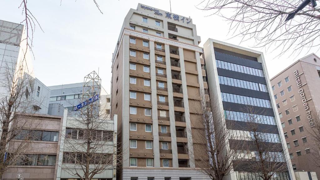 un grand bâtiment au milieu de certains bâtiments dans l'établissement Toyoko Inn Kumamoto Sakuramachi Bus Terminal Mae, à Kumamoto