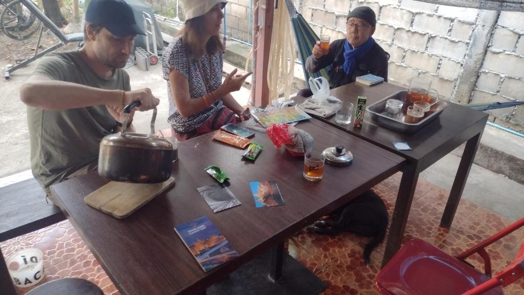 Eine Gruppe von Menschen, die an einem Tisch mit einem Topf sitzen in der Unterkunft Mae Sot Commune in Mae Sot