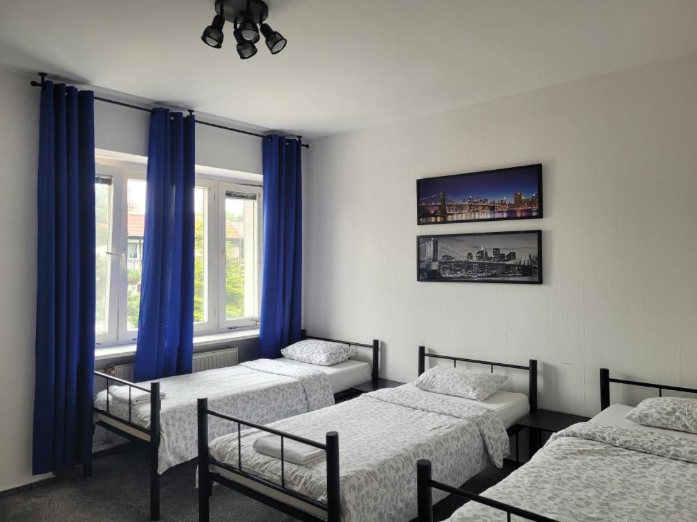 um quarto com 4 camas com cortinas azuis e janelas em Miastkovo em Poznań