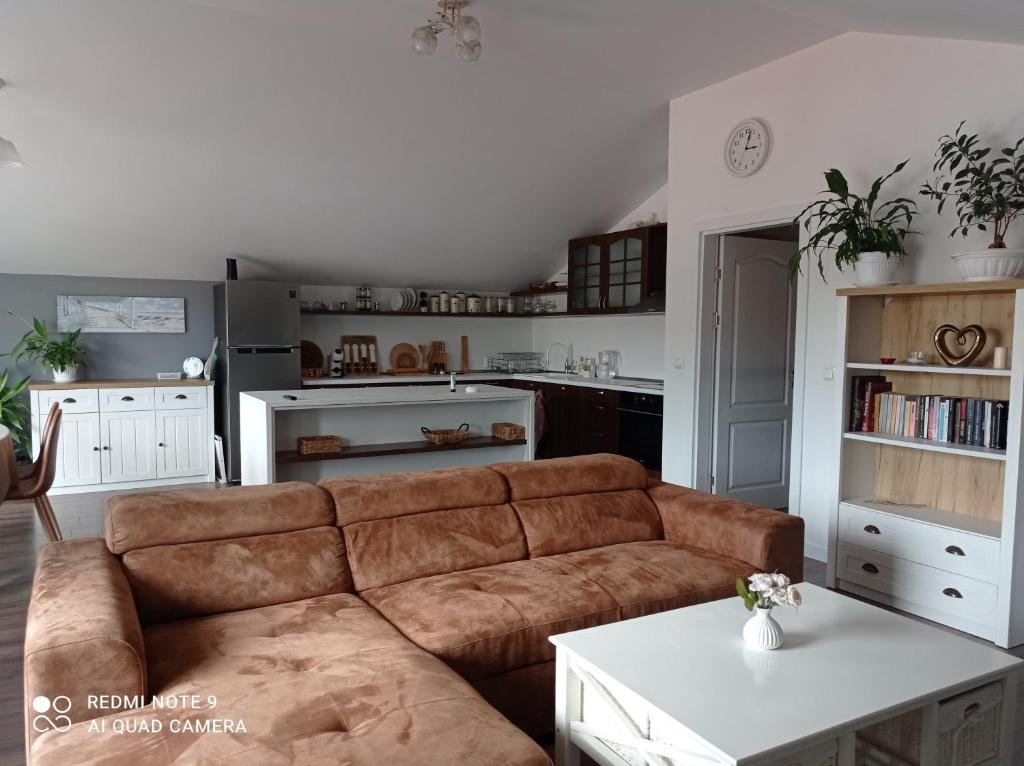 a living room with a brown couch and a kitchen at Уютна къща in Sliven