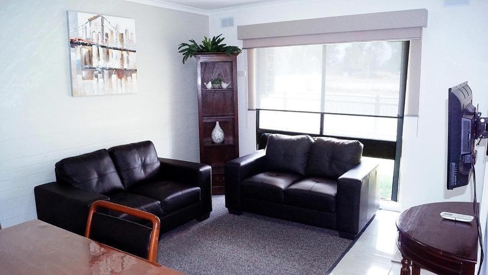 a living room with a couch and a chair and a table at Maude St Apartments in Shepparton