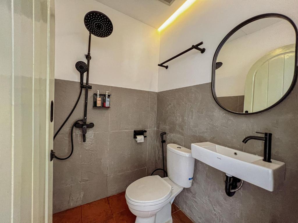 a bathroom with a toilet and a sink and a mirror at Renjana Beach House in Bira