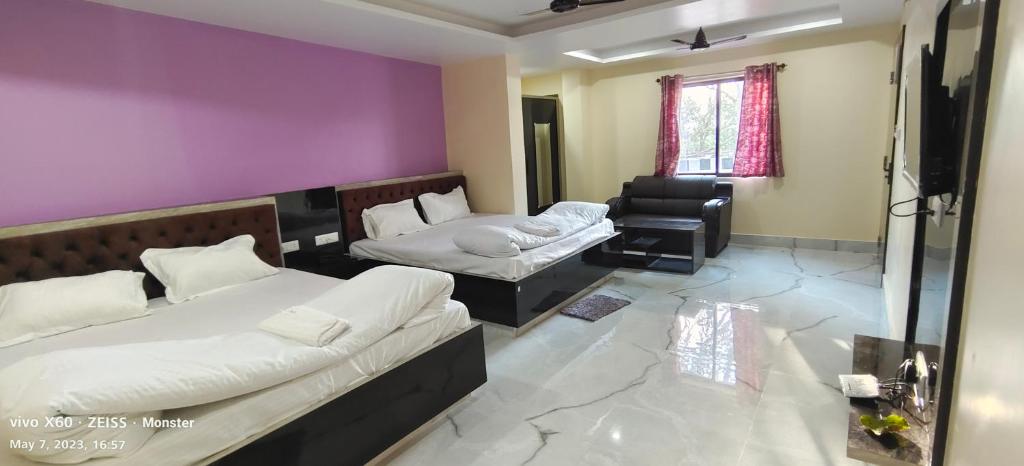 a room with two beds and a chair in it at Vaidehi Inn-A Unit of vaidehi guest house in Deoghar