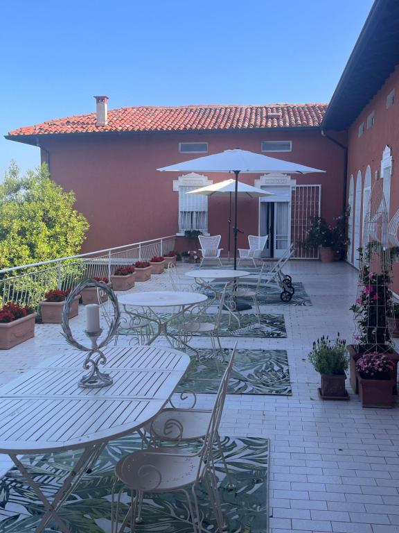 d'une terrasse avec des tables, des chaises et un parasol. dans l'établissement Villa House and Garden B&B, à Montichiari