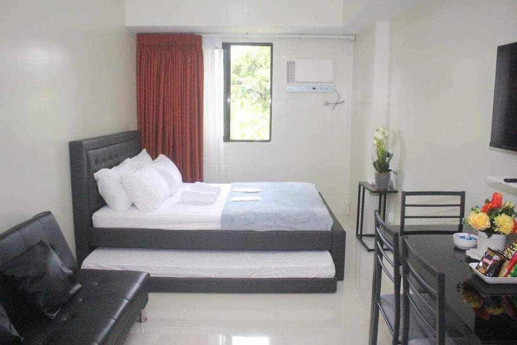 a bedroom with a bed and a couch in a room at ZackG Serene Homestay at Brenthill 210 Baguio in Baguio