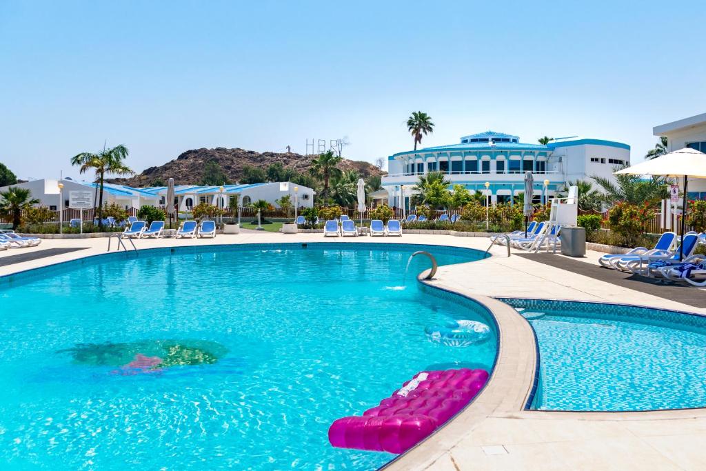 a swimming pool with chaise lounges and chairs in a resort at Holiday Beach Resort in Dibba