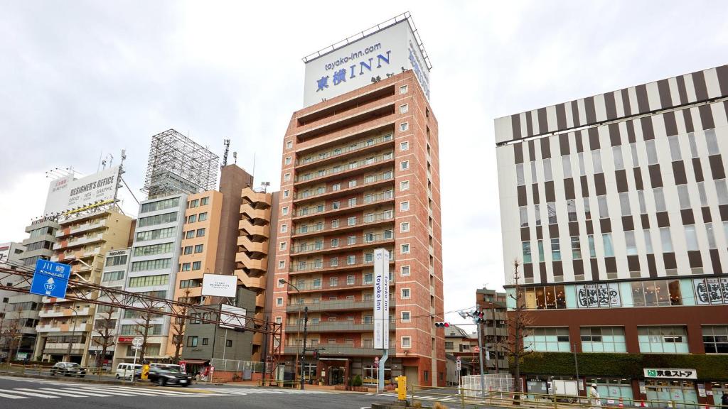 un grand bâtiment avec un panneau dans une ville dans l'établissement Toyoko Inn Tokyo Shinagawa-eki Takanawa-guchi, à Tokyo