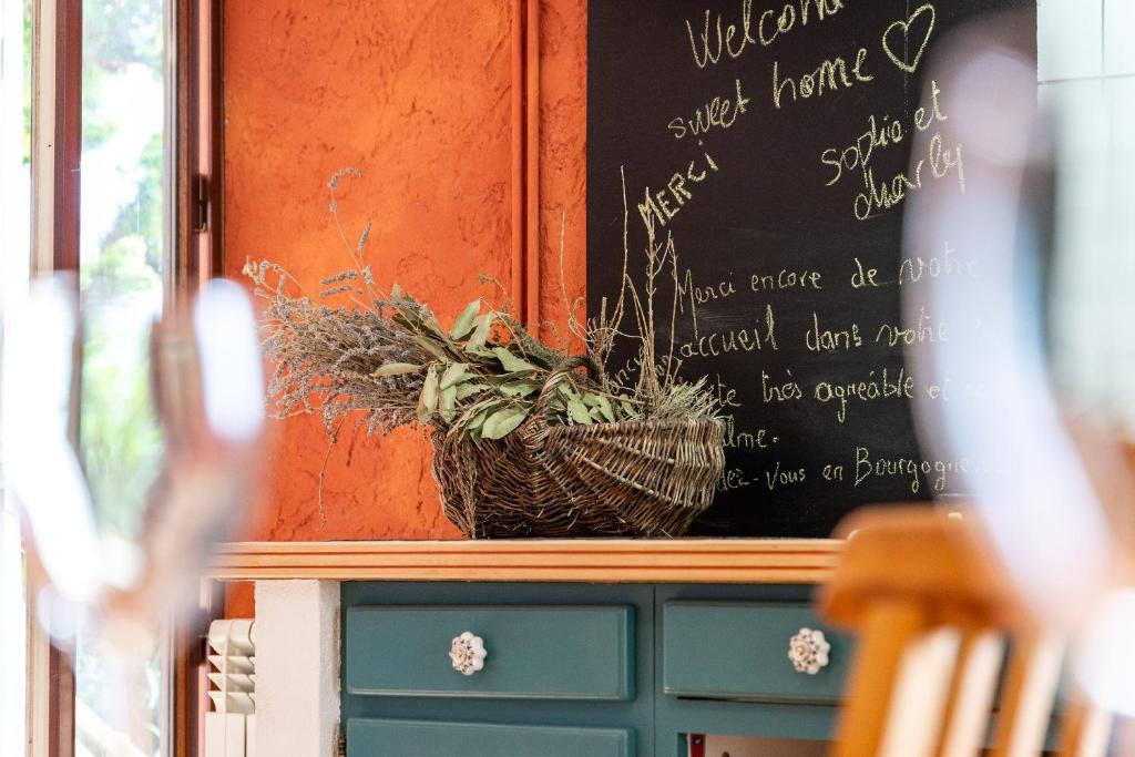a chalkboard on a wall with a basket of plants at Au petit bonheur in Bédoin