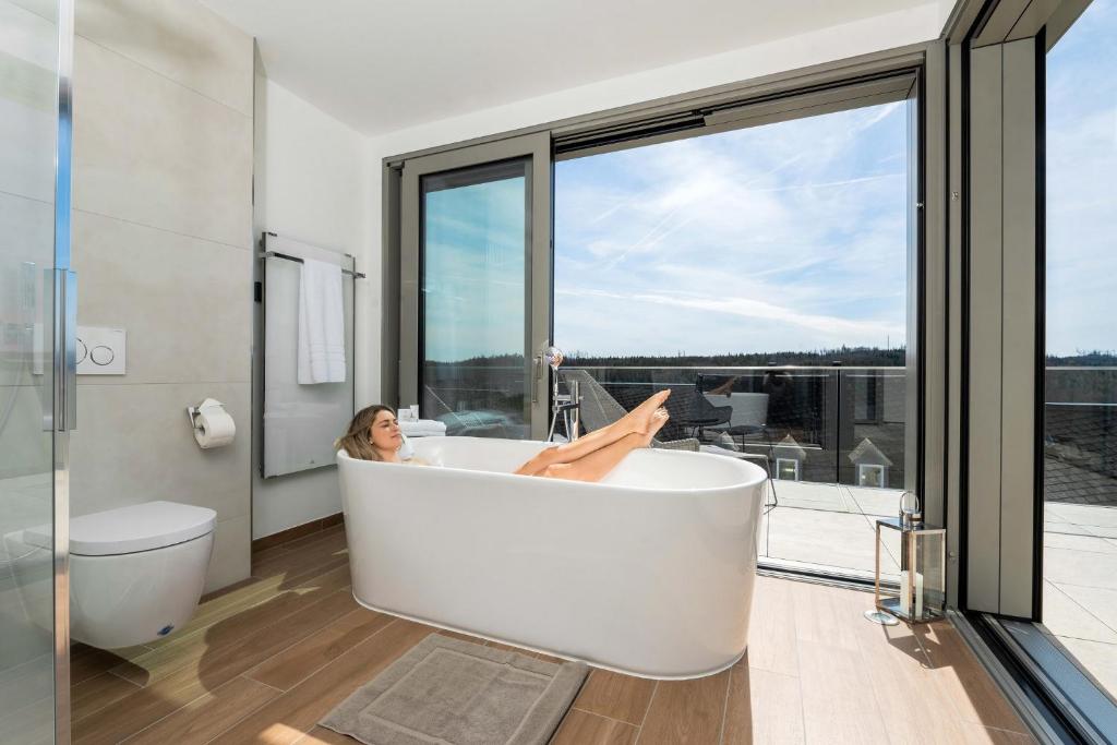 a woman laying in a bath tub in a bathroom at Lichtenberg Lodges in Lichtenberg