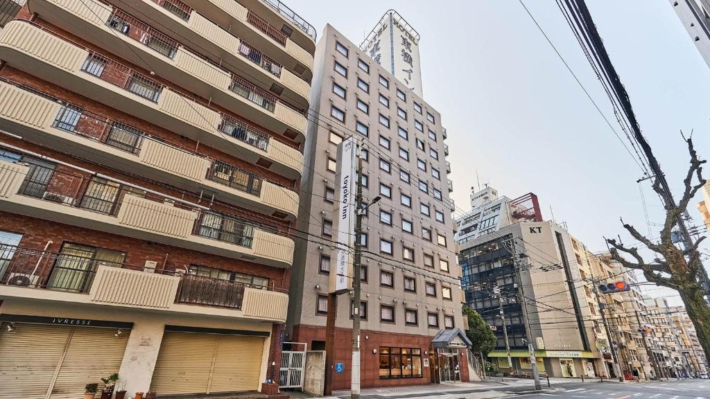 um edifício alto numa rua da cidade com edifícios em Toyoko Inn Osaka Temmabashi Otemae em Osaka