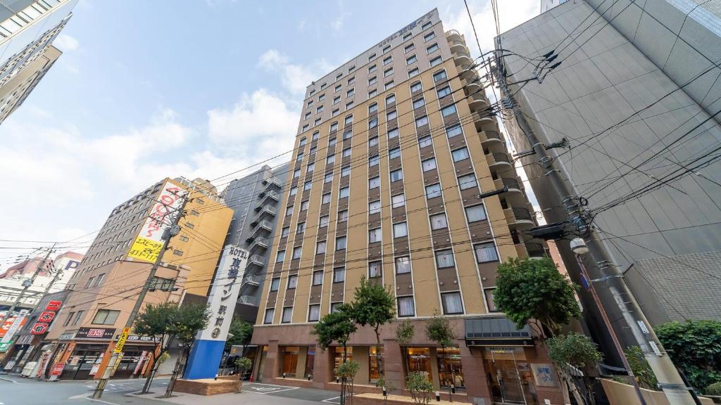 un edificio alto en una calle de la ciudad con edificios en Toyoko Inn Hakata-guchi Ekimae, en Fukuoka