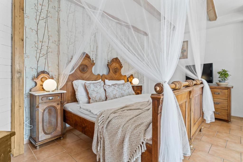 a bedroom with a wooden bed with a canopy at Pension a restaurace Regina in Větřní